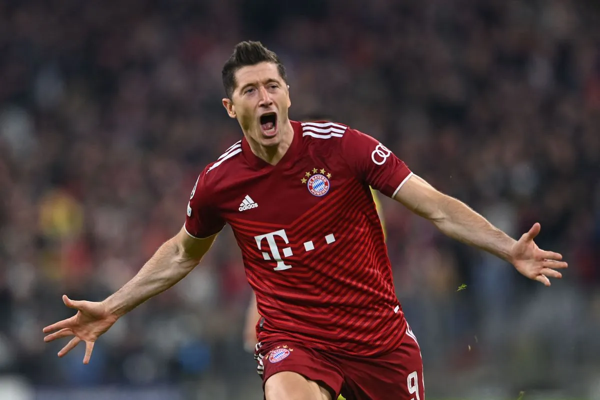 Robert Lewandowski celebrates a goal in a Bayern Munich jersey with his arms outstretched and mouth open in excitement.