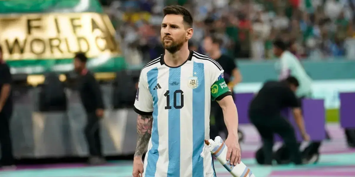 Lionel Messi walking on the field in Argentina’s national team jersey during the FIFA World Cup, holding a captain's armband with a focused expression.