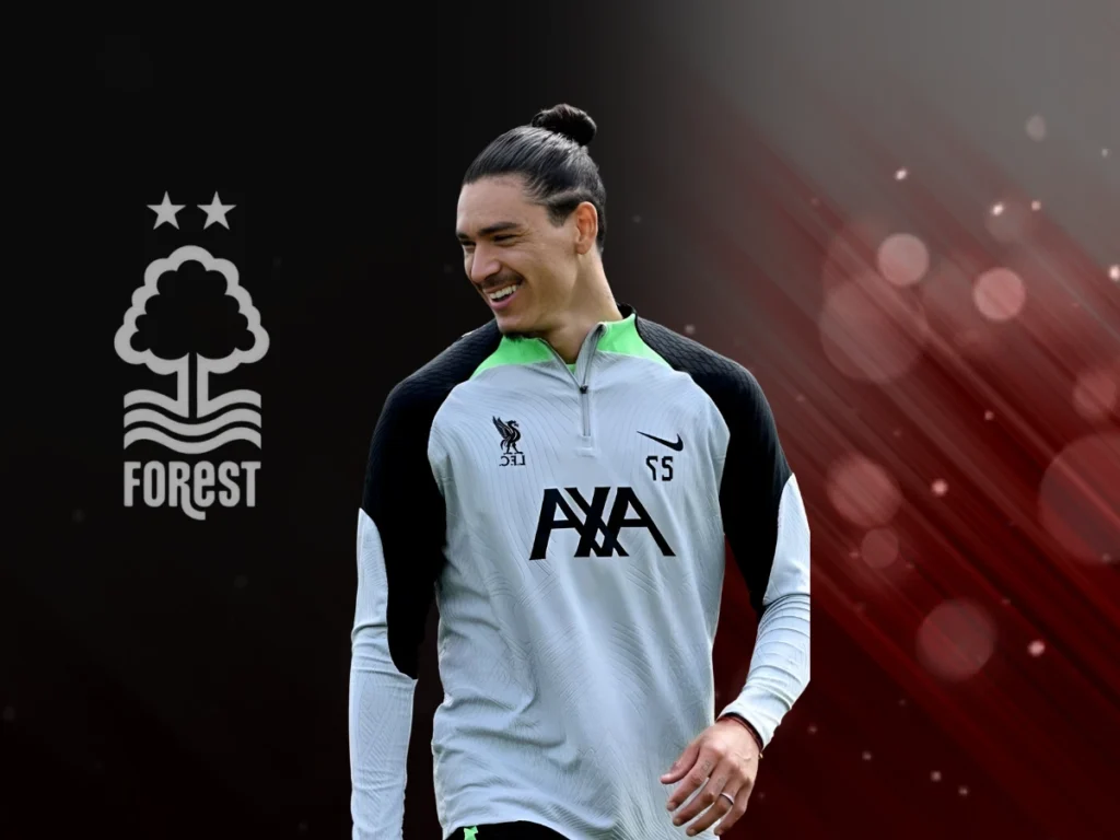 Darwin Núñez in a Liverpool training kit, smiling with a Nottingham Forest logo in the background.