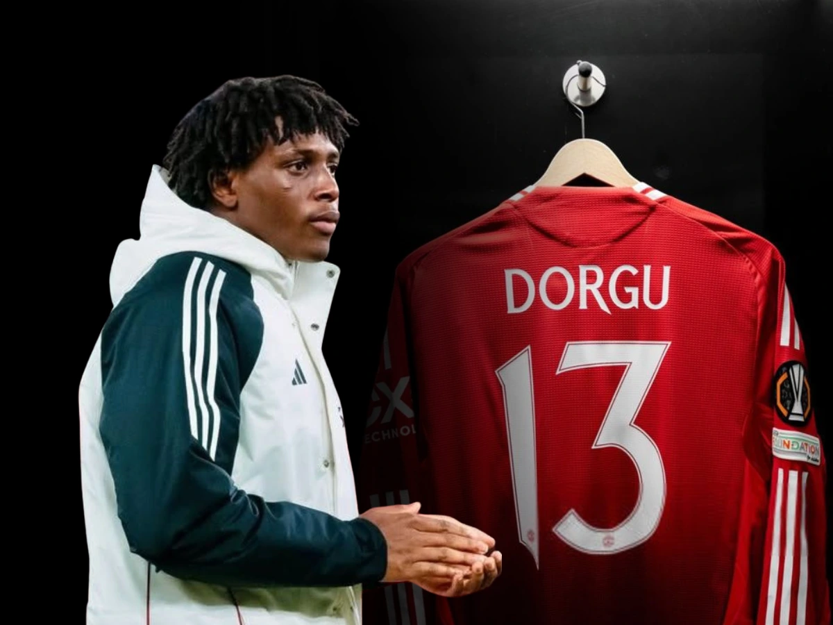 A digitally edited image of Patrick Dorgu wearing a white and black Adidas jacket, standing next to a red jersey with his name and the number 13 on it, hanging on a hook.