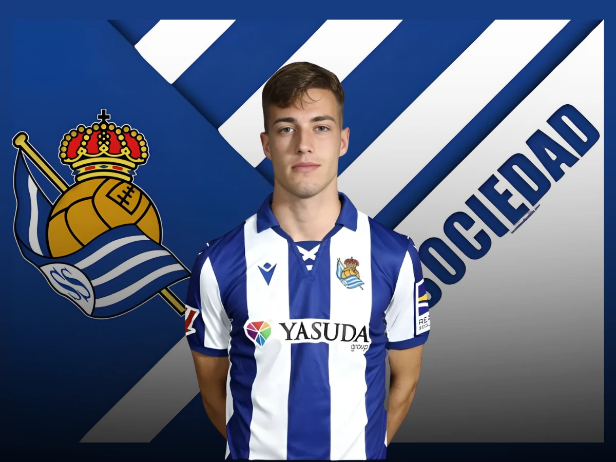 Luka Sučić wearing a Real Sociedad jersey, with the club's logo and name in the background.