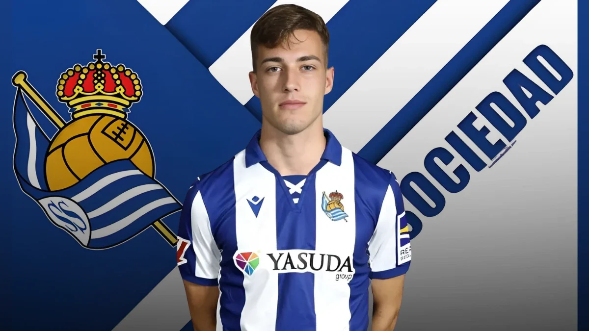 Luka Sučić wearing a Real Sociedad jersey, with the club's logo and name in the background.