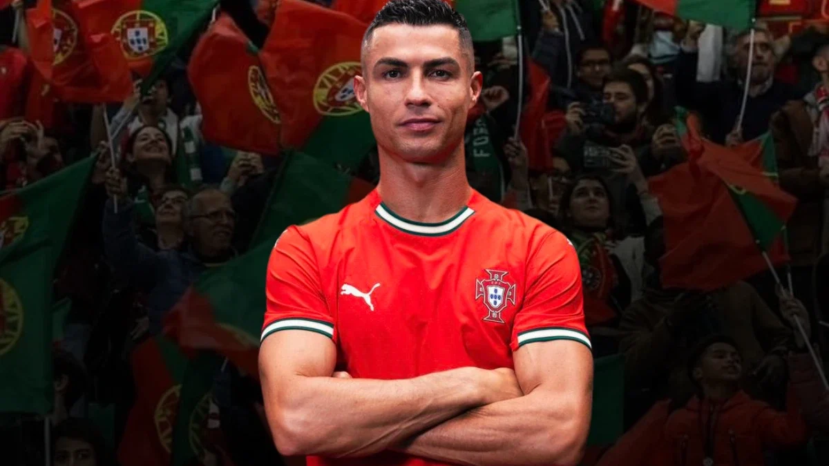 Cristiano Ronaldo stands confidently with his arms crossed, wearing Portugal's red national team jersey. Behind him, a crowd of passionate Portuguese fans waves green and red flags with the national emblem, creating an energetic and patriotic atmosphere.